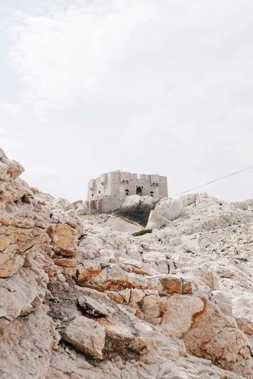 Fort de Pomègues vu d'en bas depuis un sentier rocheux par temps nuageux