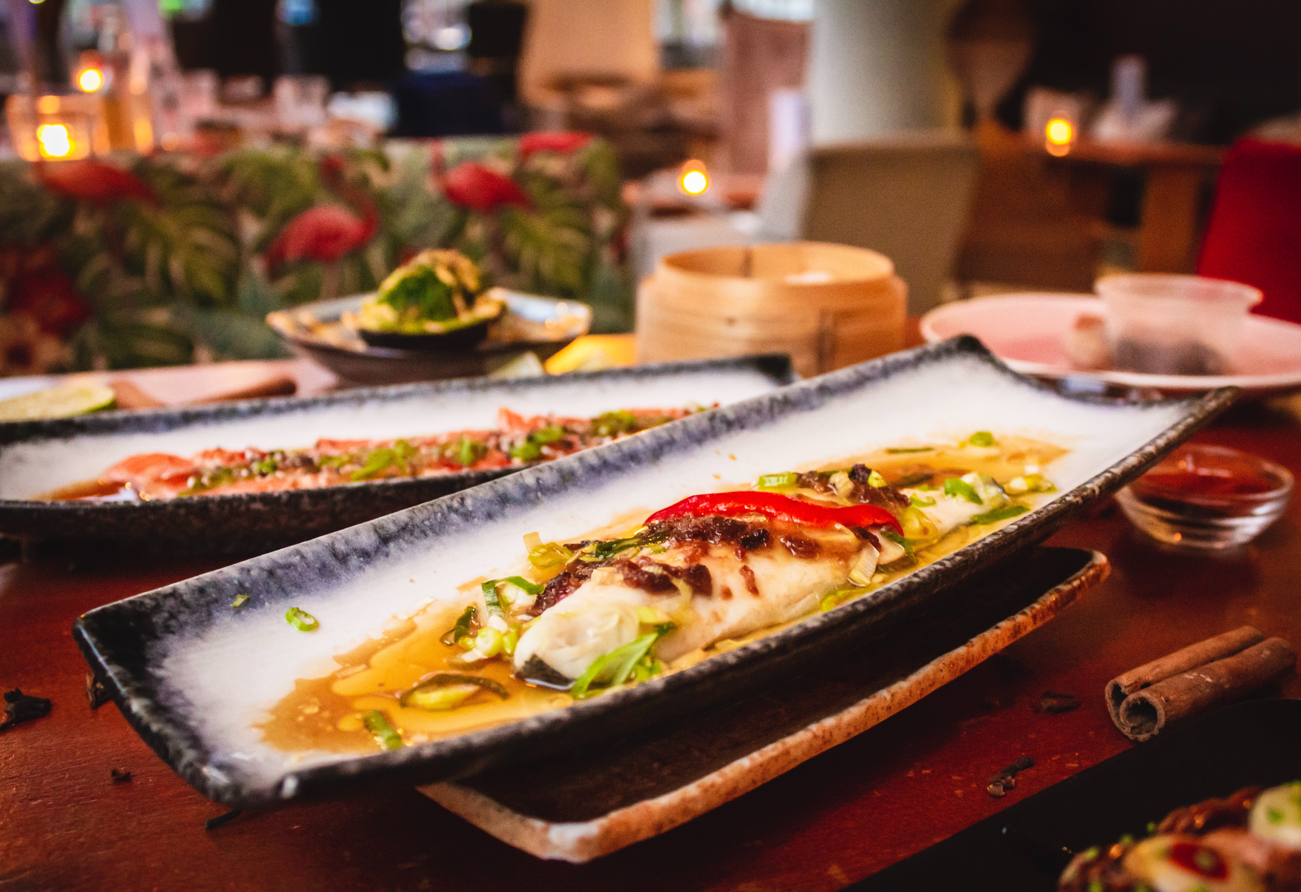 Poisson finement dressé avec légumes, servi sur une assiette longue dans un restaurant asiatique