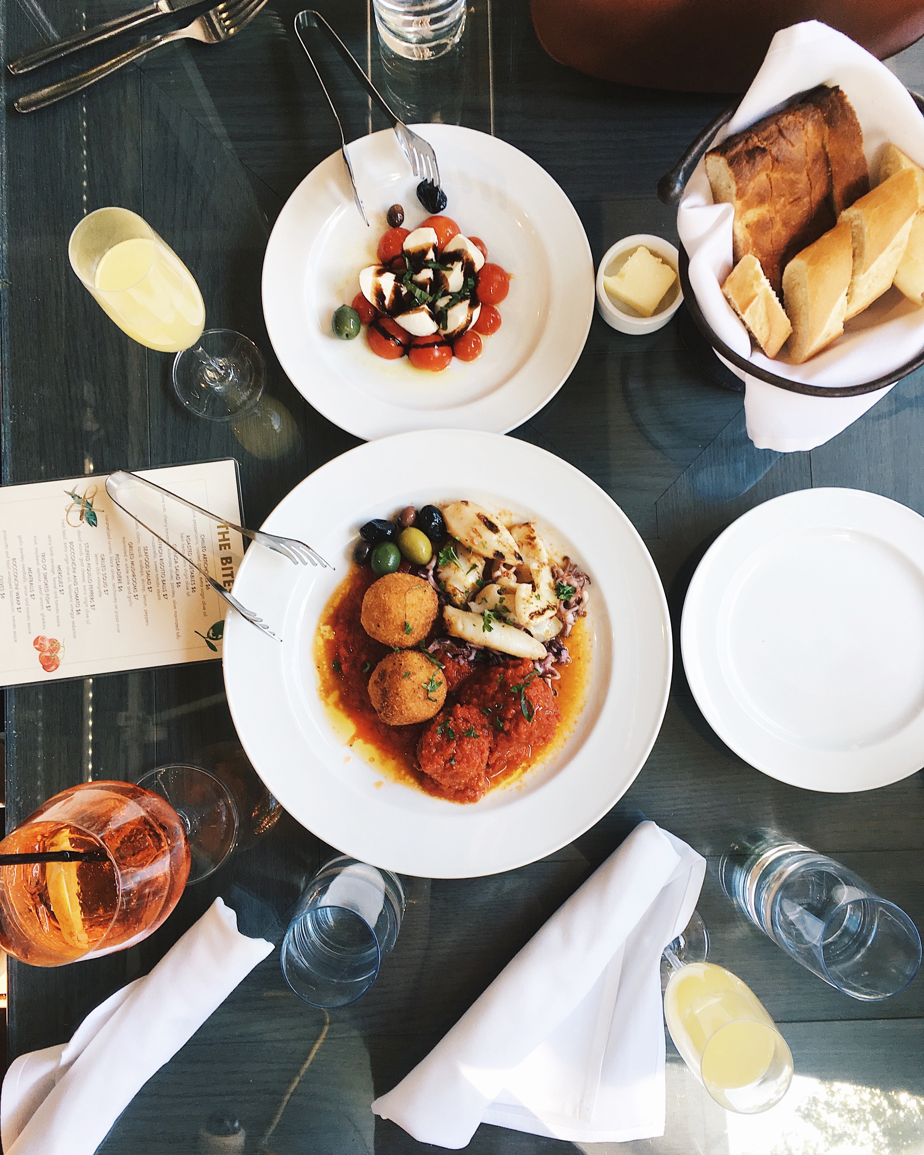 Assiette de croquettes, petits calamars, olives noires et sauce, présentée dans un cadre élégant